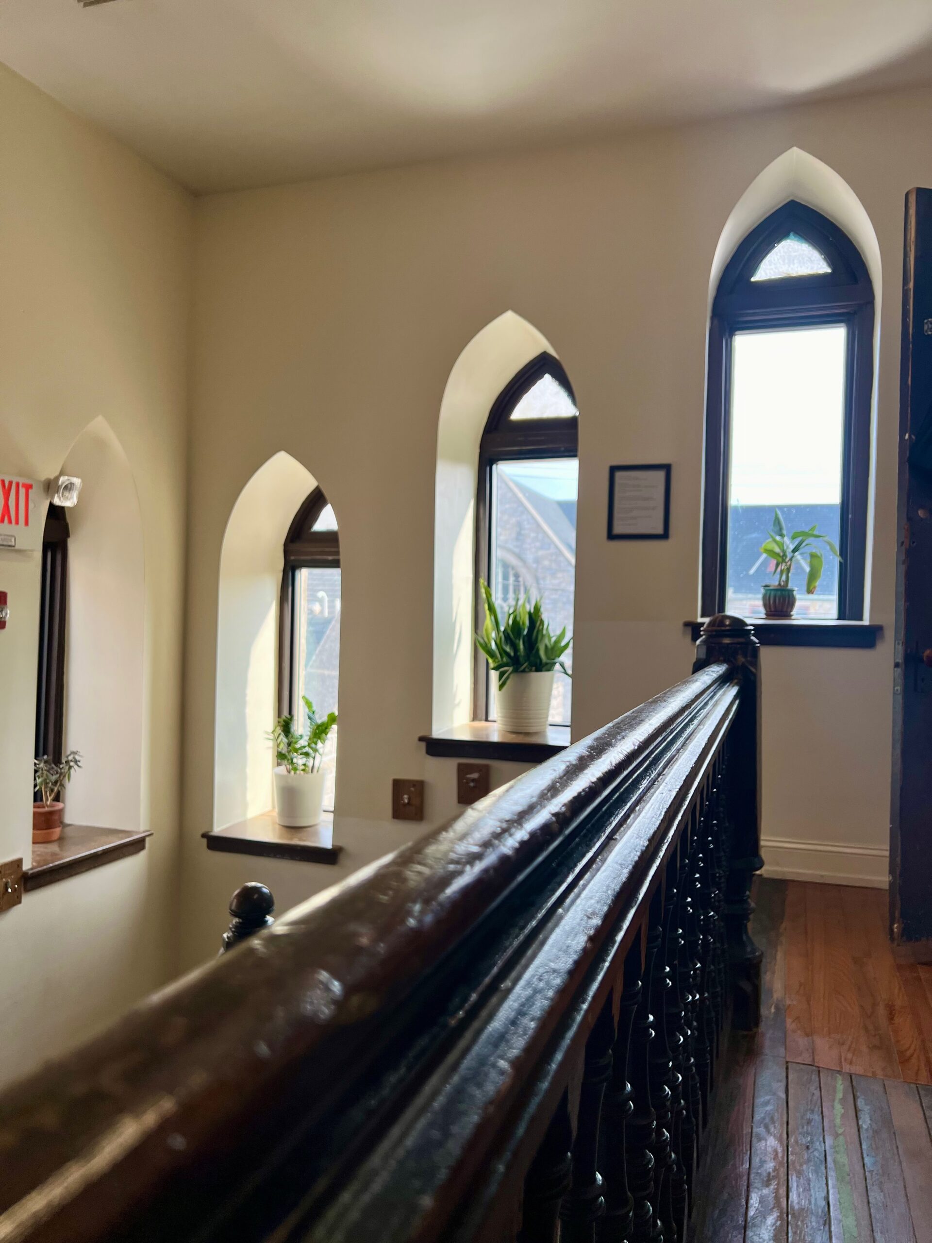 A series of arched windows with plants on each sill in the stairwell.